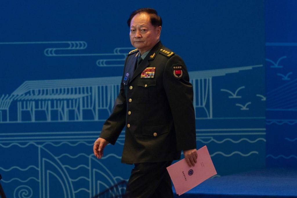 Military official walking with documents.
