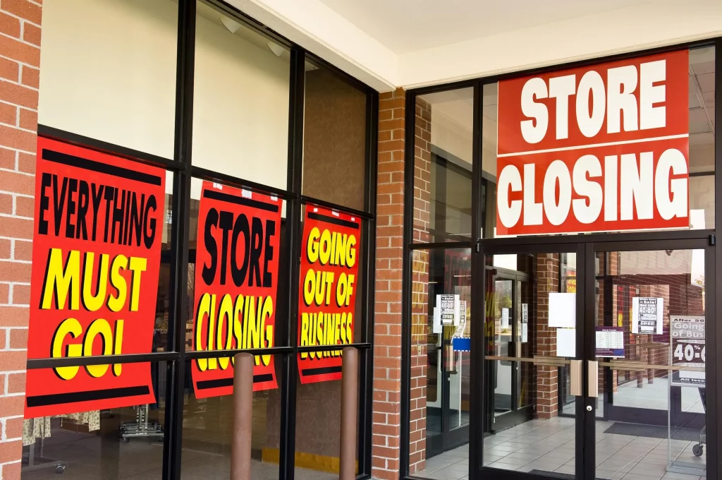 Empty retail storefront with closing sale signs, representing global shop closures and sales loss in 2025