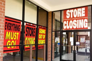 Empty retail storefront with closing sale signs, representing global shop closures and sales loss in 2025