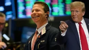 President Donald Trump speaking at podium with oil price graph and DHS shutdown news headlines in background, April 2026