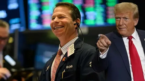 President Donald Trump speaking at podium with oil price graph and DHS shutdown news headlines in background, April 2026