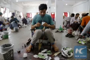 Skilled craftsman in Sialkot Pakistan stitching a handmade leather football by hand in a traditional workshop