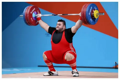 Nooh Dastagir Butt lifting a heavyweight barbell during an international weightlifting competition representing Pakistan.