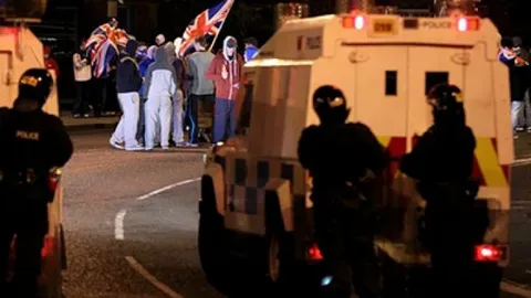 Police vehicles and protesters during Belfast riots today in Northern Ireland streets