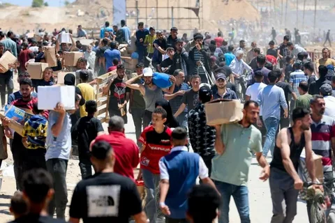 Palestinians gather among damaged buildings in Gaza City during the humanitarian crisis in 2026
