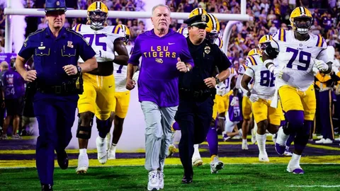 College football head coach walking onto stadium field during 2026 coaching changes season