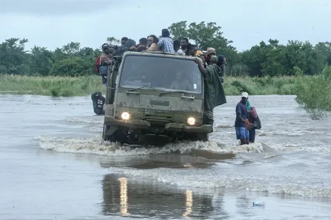 Floods in Africa today showing flooded streets in Mozambique with displaced families wading through water