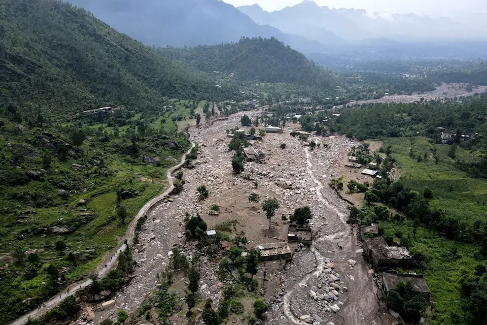 Rescue workers wading through flooded streets during Pakistan flash floods in a mountainous KPK district