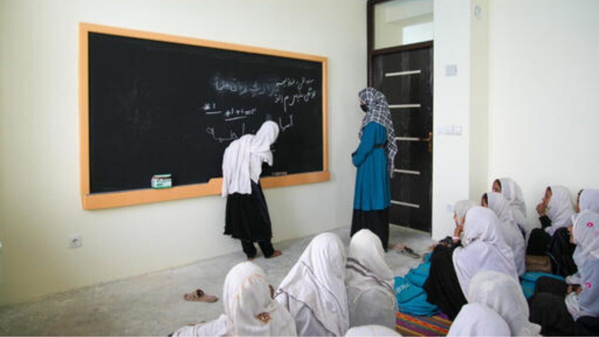 Afghan girls sitting outside a closed school building in Afghanistan