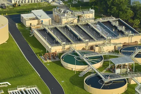 Aerial view of a large wastewater treatment plant with circular tanks and treatment basins