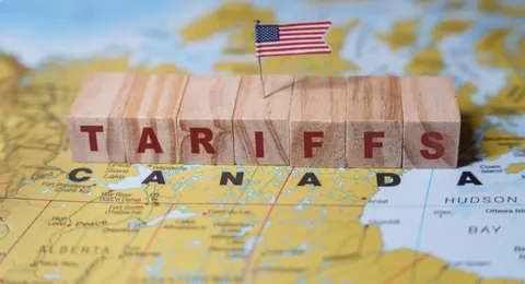Cargo containers and Canadian flag at a shipping port representing US Canada tariffs today