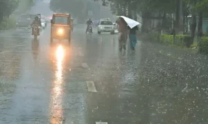 Heavy rain in Punjab flooding a city street with cars and motorbikes wading through water