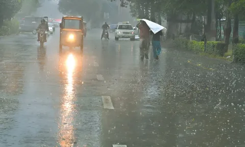 Heavy rain in Punjab flooding a city street with cars and motorbikes wading through water