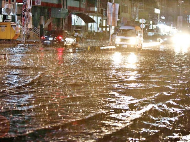 Flooded road in Rawalpindi with cars wading through rainwater during heavy monsoon downpour