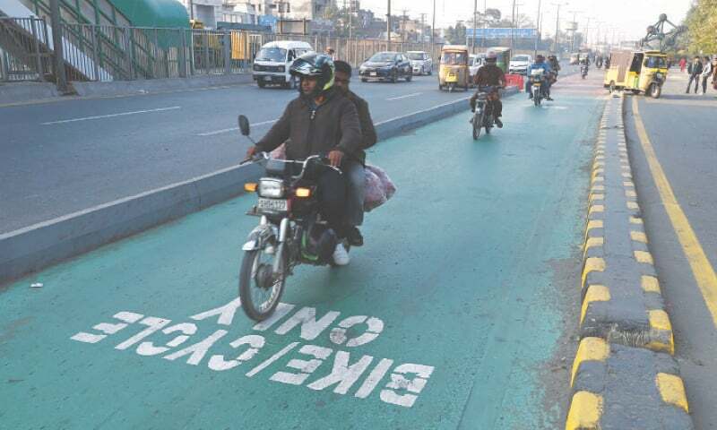 Motorcyclists riding in a designated motorcycle lane on a busy Lahore road