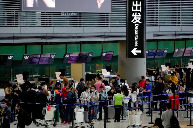 Traveler holding a Chinese passport at an airport security checkpoint, representing China's exit ban rules