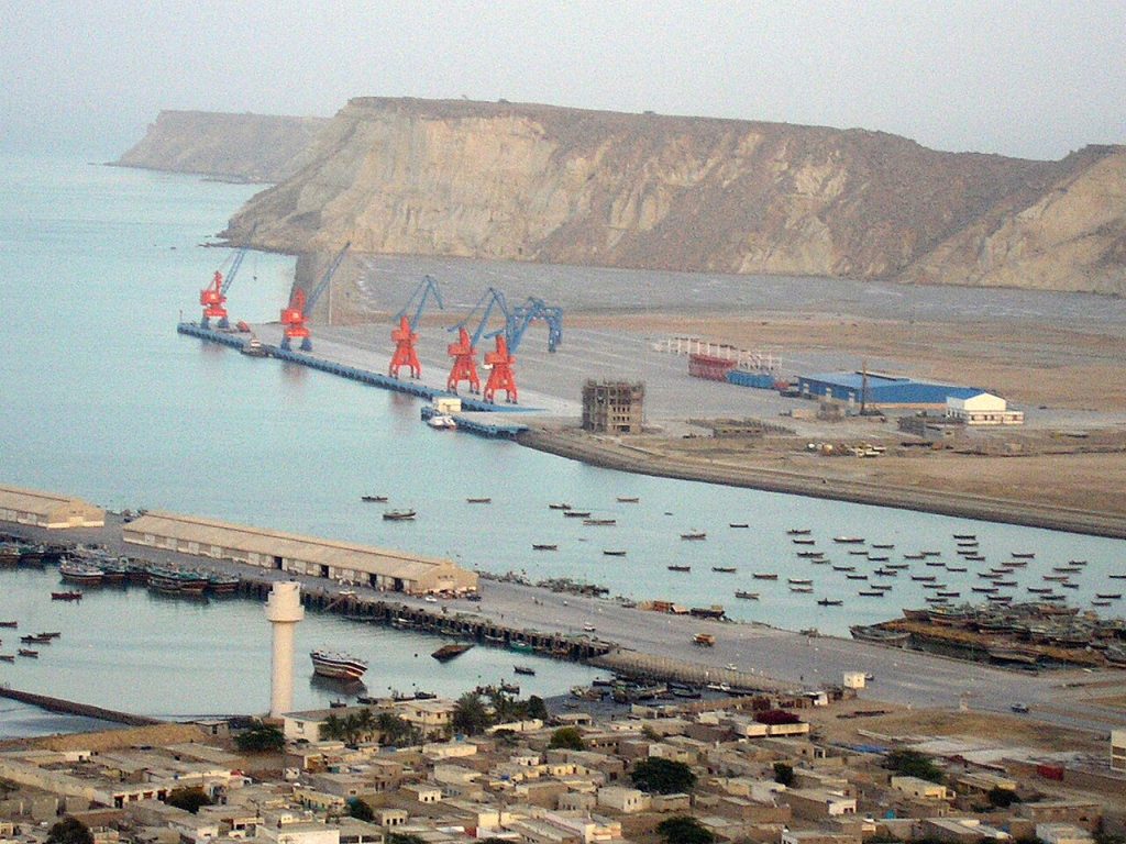 Cargo ships docked near Gwadar Port with the Arabian Sea coastline, representing growing Pakistan Oman port connectivity