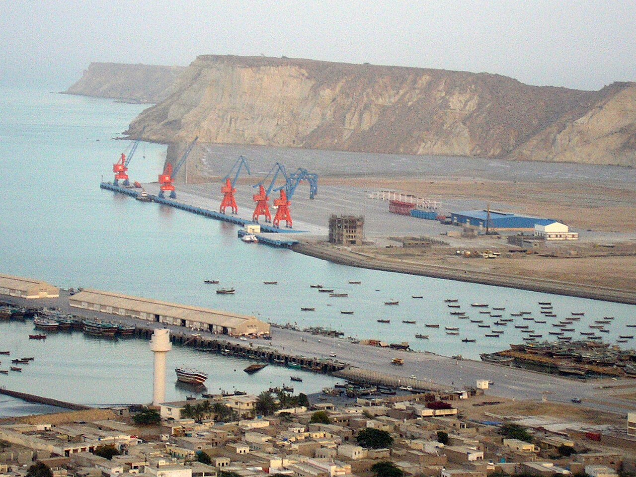 Cargo ships docked near Gwadar Port with the Arabian Sea coastline, representing growing Pakistan Oman port connectivity