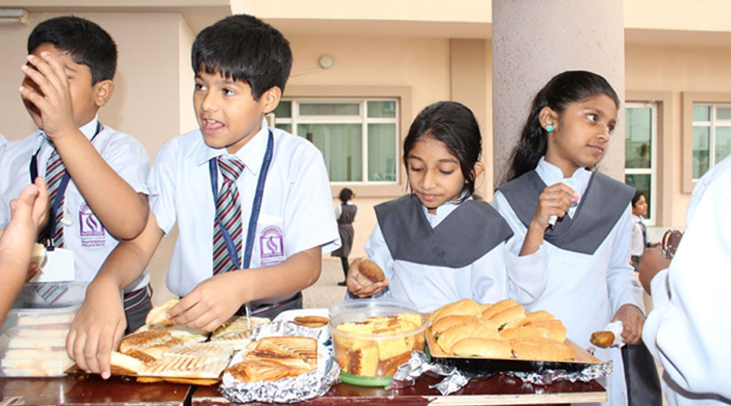 Roadside food stall selling packaged snacks near an Indian school gate