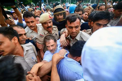 Rahul Gandhi standing on a police barricade and waving the Indian flag during an opposition march near the Election Commission in New Delhi